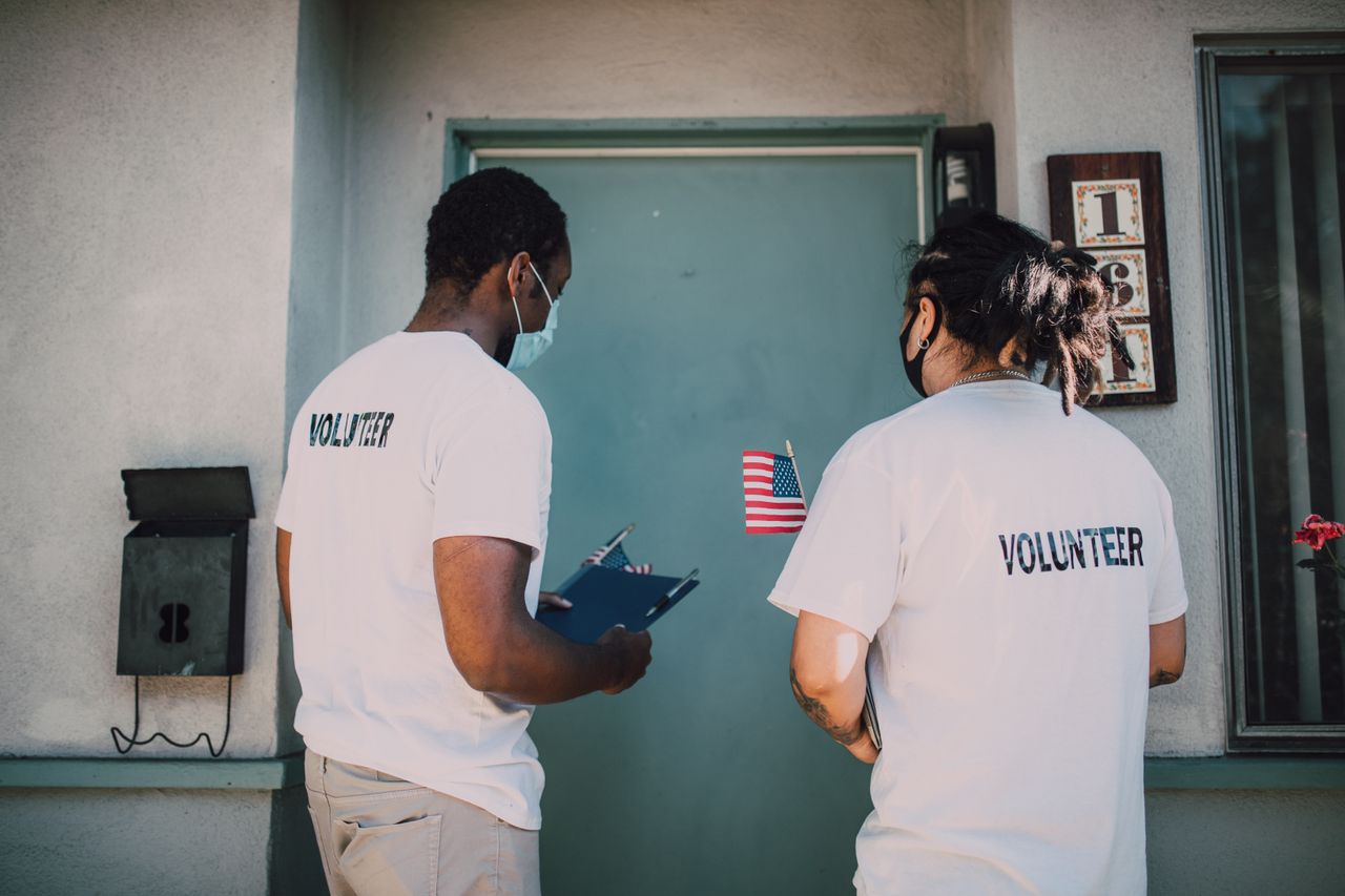 about-img Two volunteers wear masks and visit community homes, engaging in outreach activities.