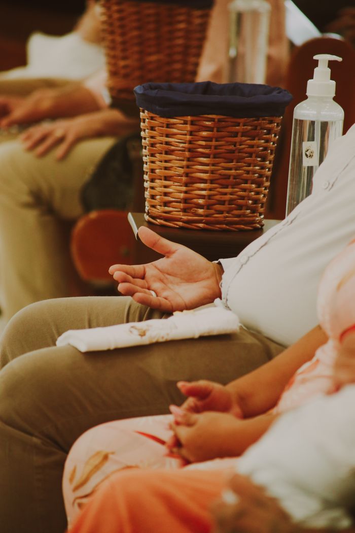 A close-up shot of people sitting with donation baskets and sanitizer, suggesting community gathering and charity.